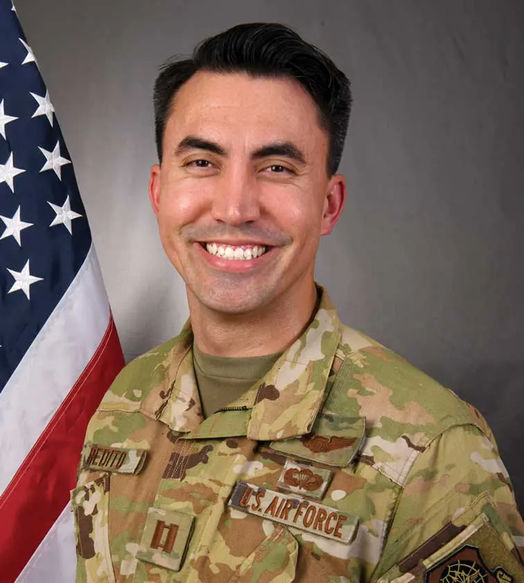 A man in military uniform with an american flag behind him.