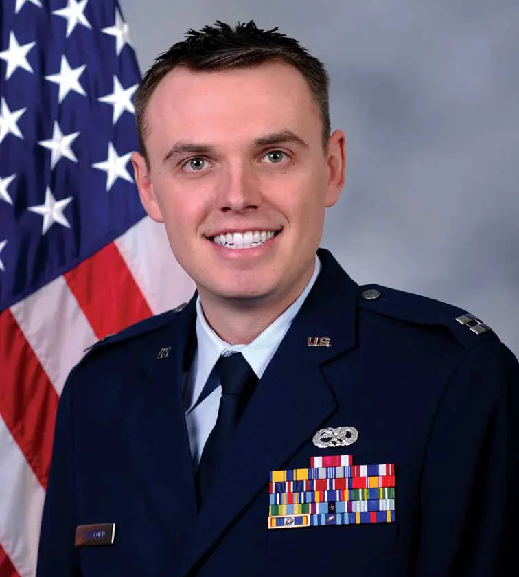A man in uniform with an american flag behind him.
