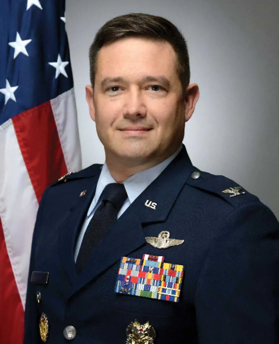 A man in military uniform standing next to an american flag.