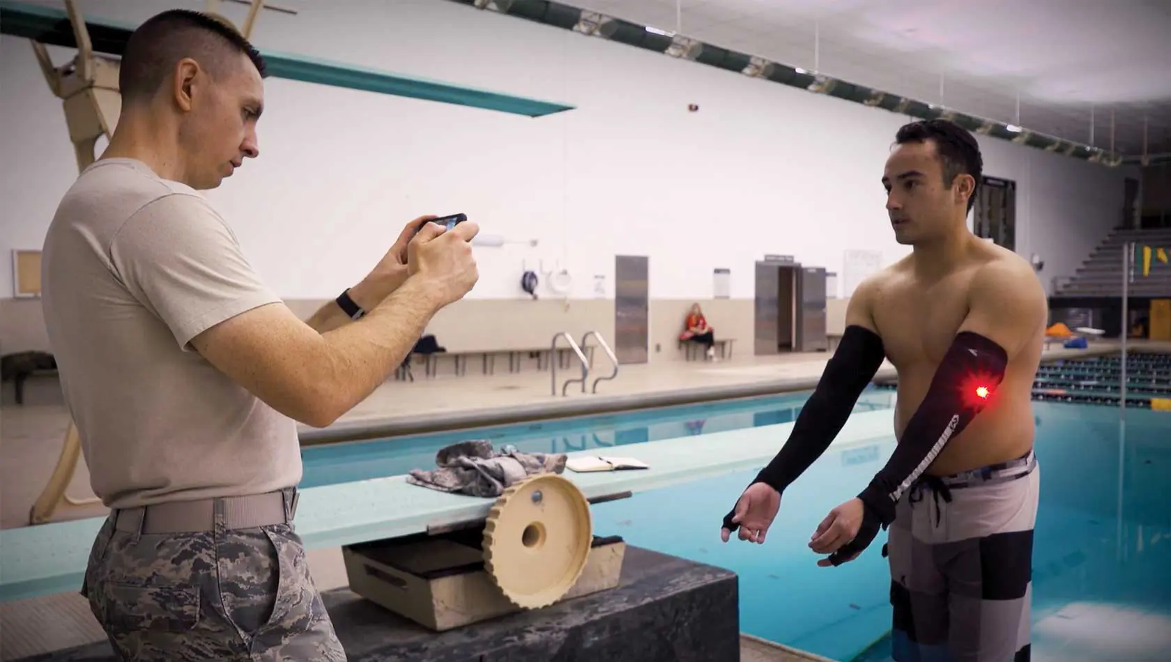 Two men in a pool with one holding something