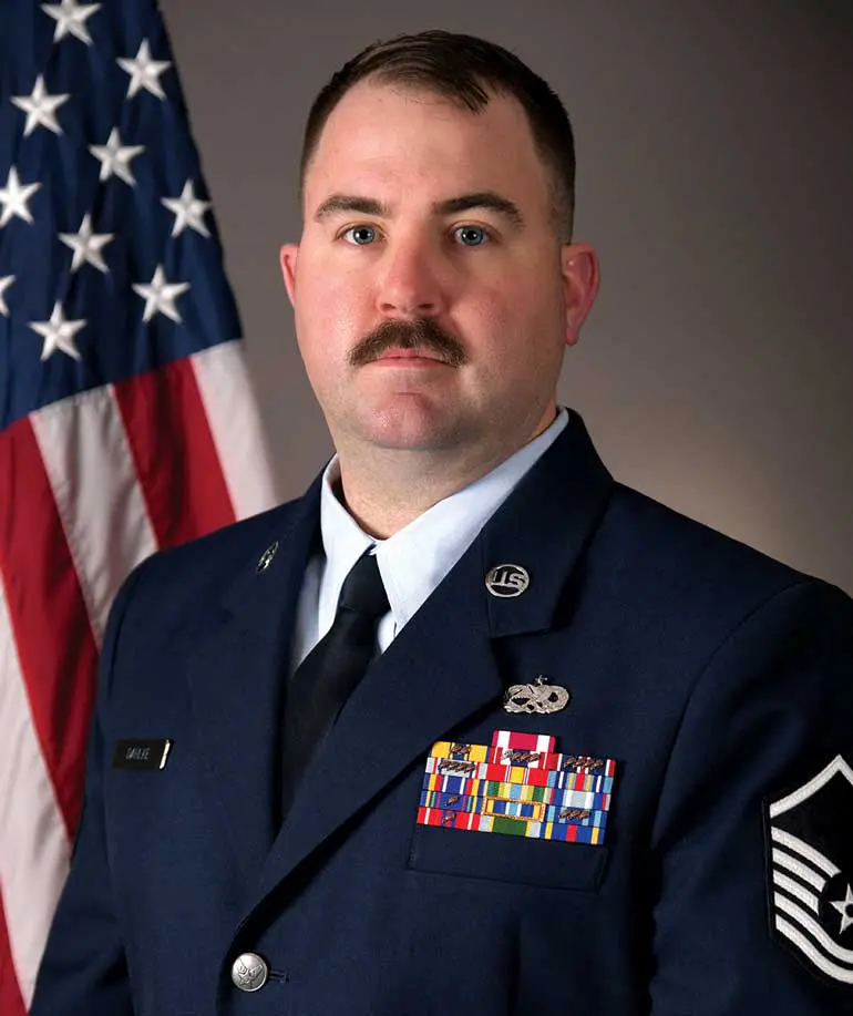 A man in uniform with an american flag behind him.