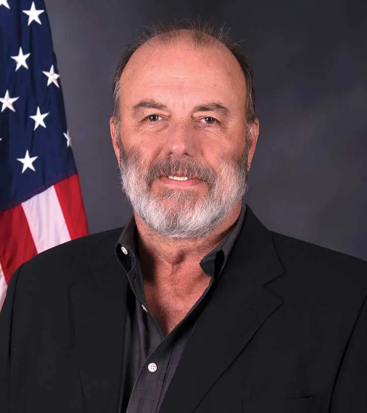 A man with a beard and mustache wearing a black jacket.