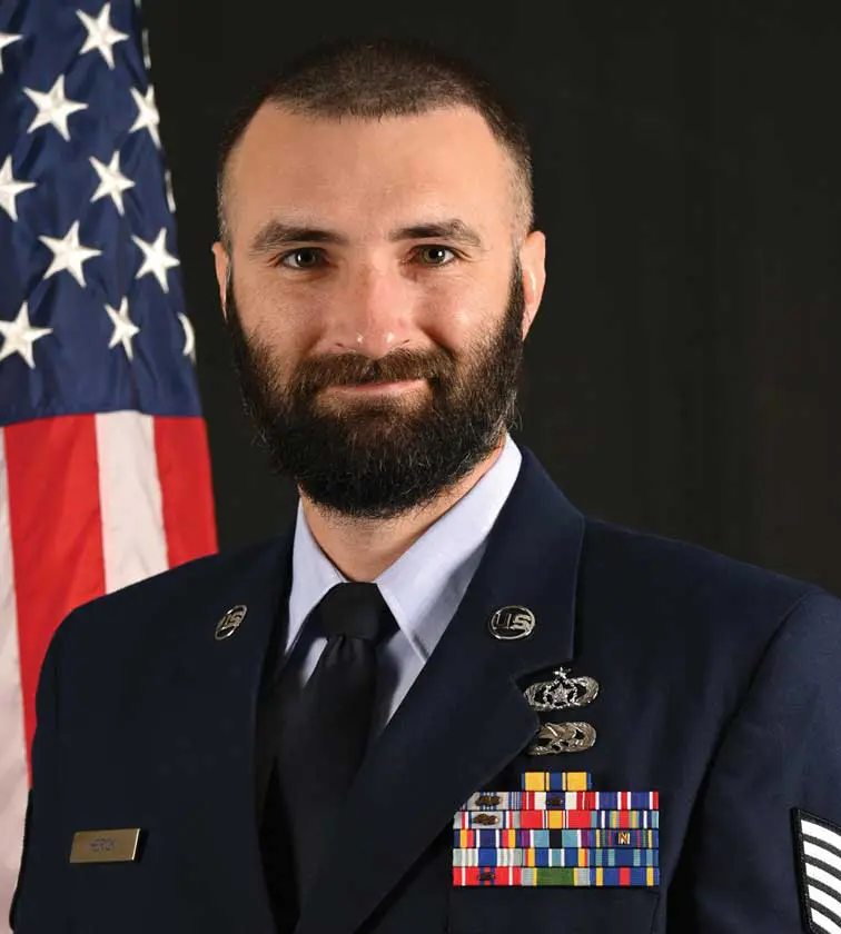 A man in uniform with a flag behind him.