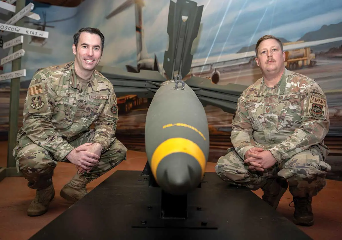 Two men in military uniforms sitting next to a bomb.