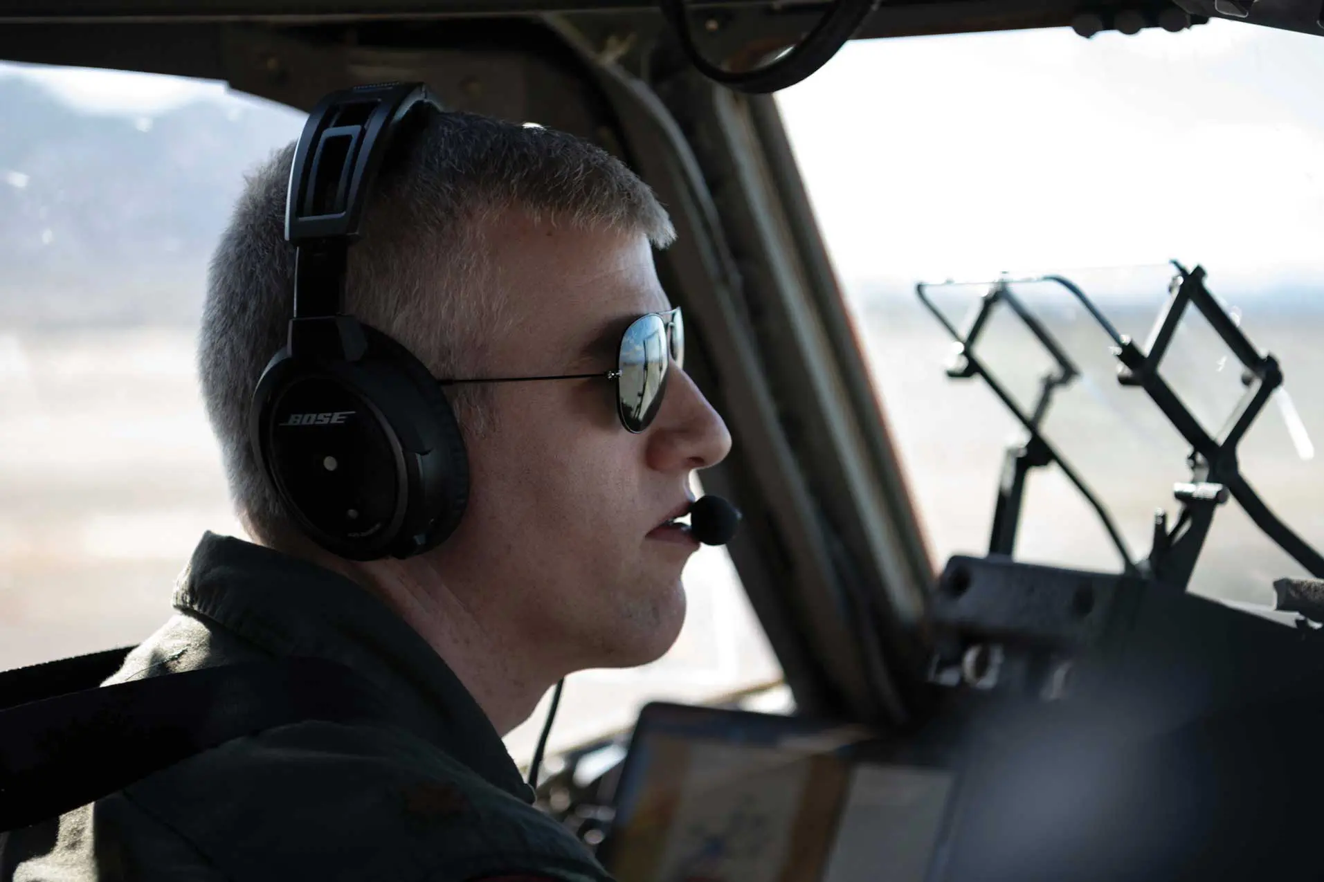 Maj David Gourdin in the pilot seat in sunglasses and headphones on looking out the aircraft.