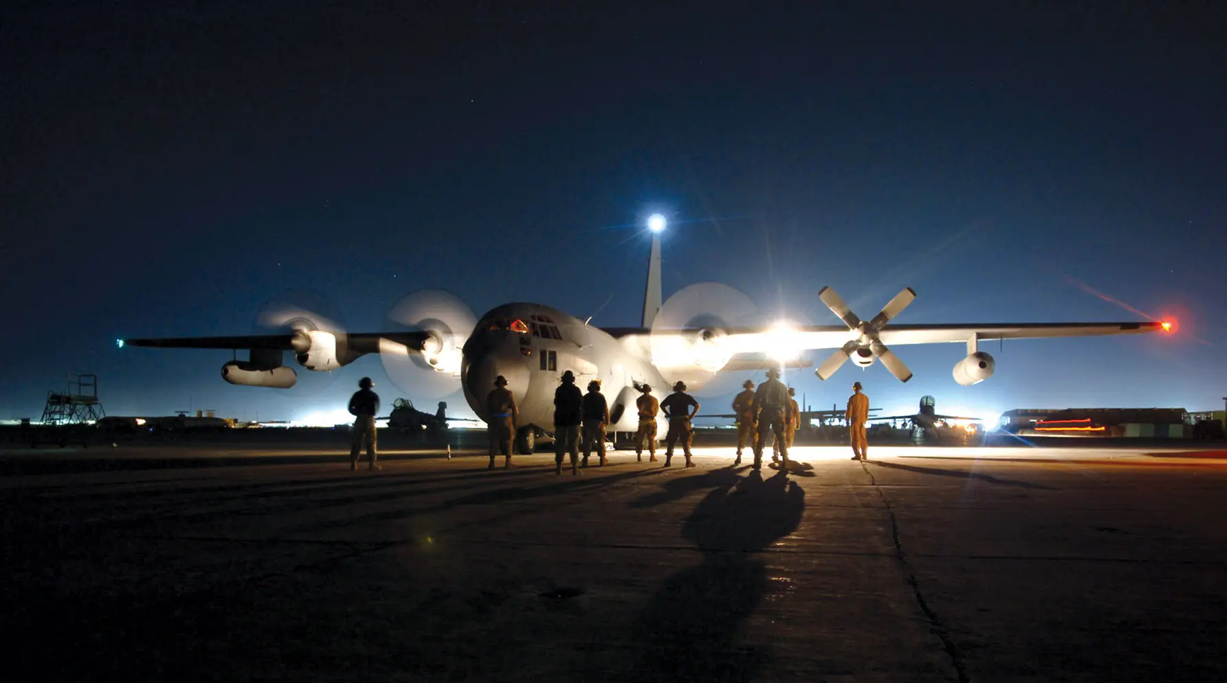 Maintainers at Bagram Air Force Base, Afghanistan, stand around an EC-130H aircraft as the aircrew starts the engines.