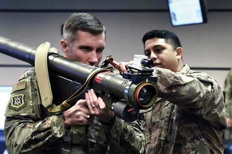 Two soldiers are holding a large device.