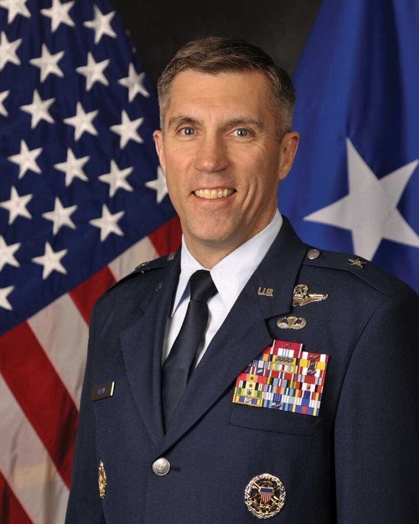 A man in military uniform standing next to an american flag.