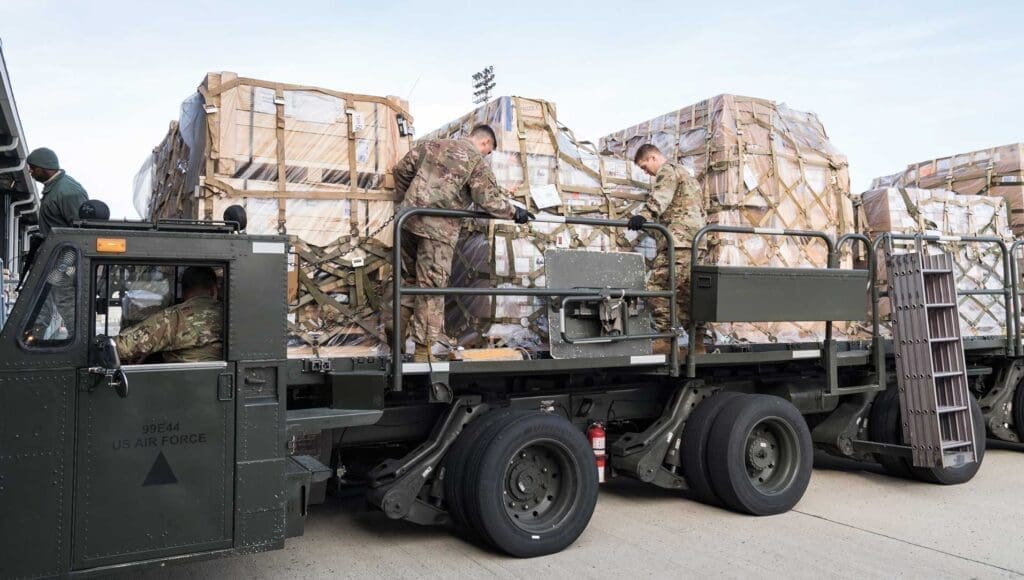 A truck with two men standing on the back of it.