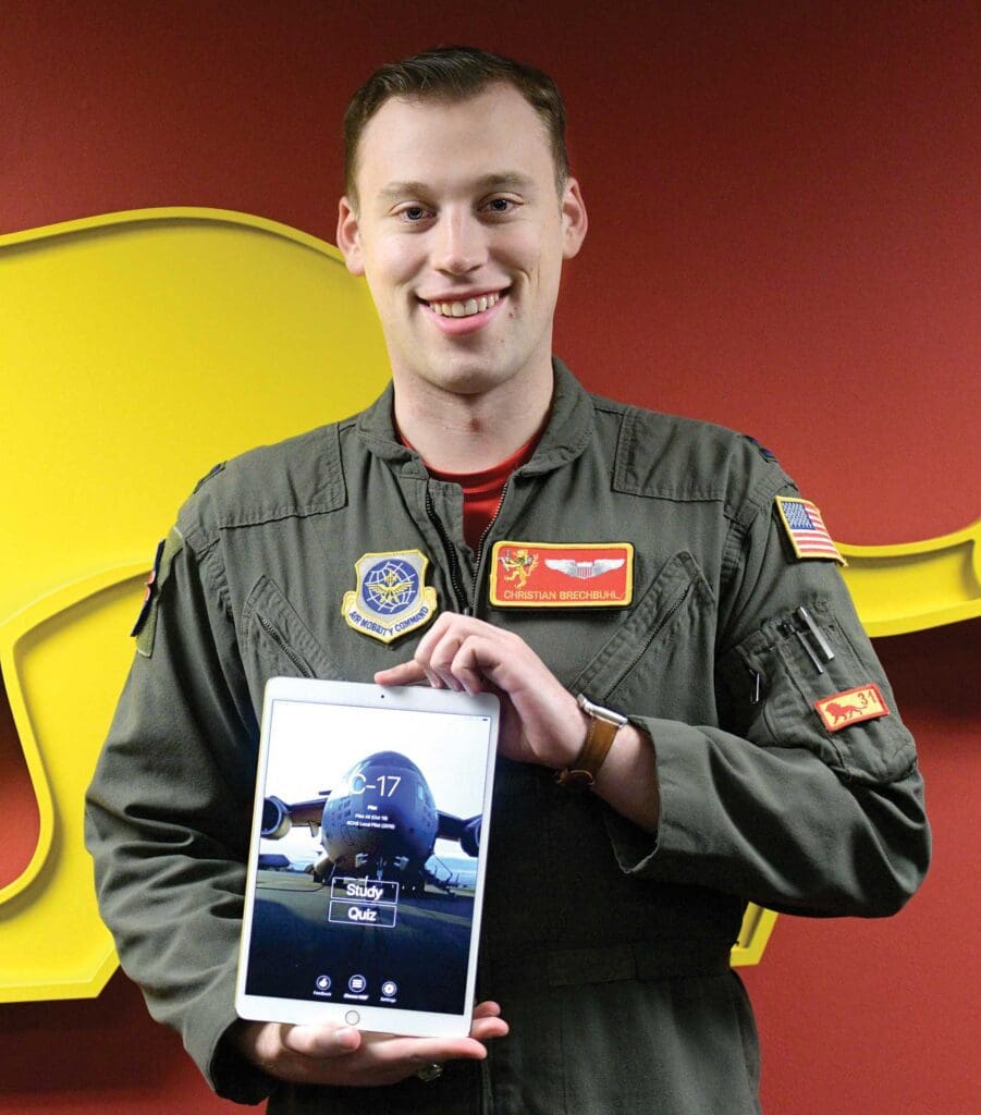 A man holding an ipad in front of a yellow elephant.
