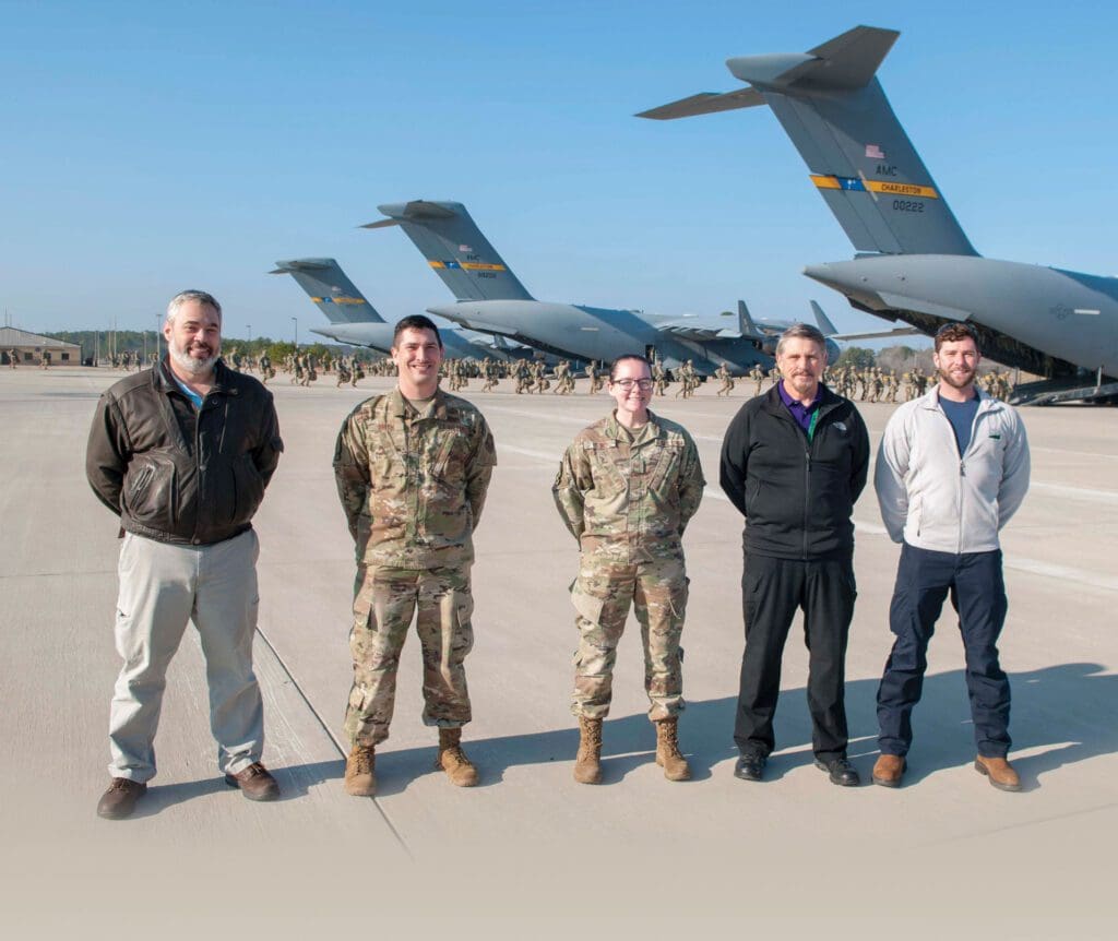Five men standing in front of a line of planes.