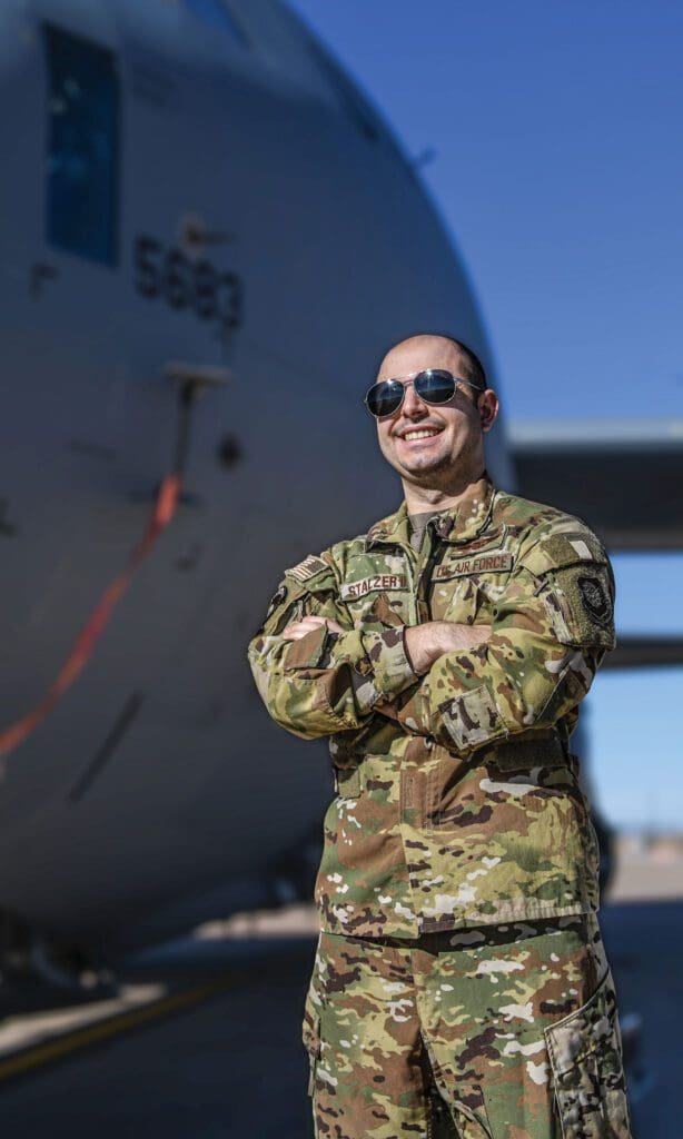 A man in military fatigues standing next to an airplane.