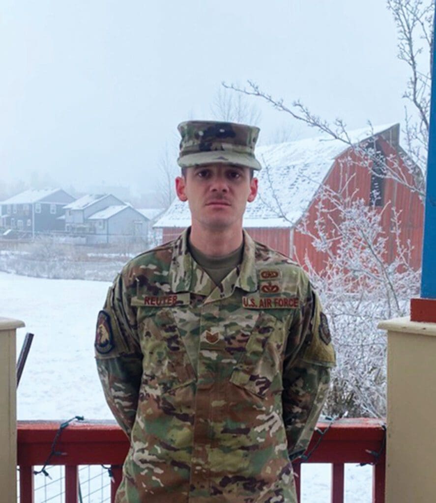 A soldier standing in front of some snow covered trees.