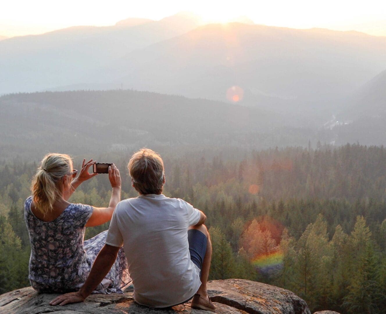 Two people sitting on a rock looking at the view