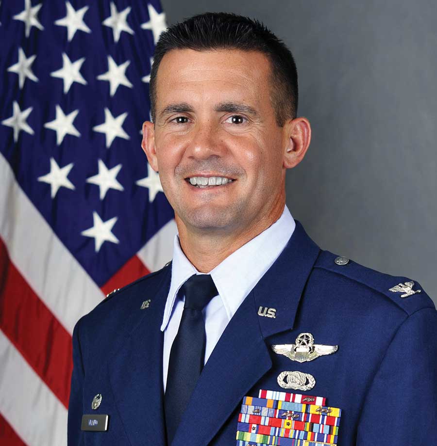 A man in military uniform with an american flag behind him.