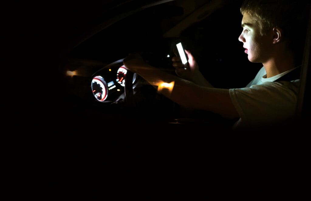 A person in the dark holding up their phone.