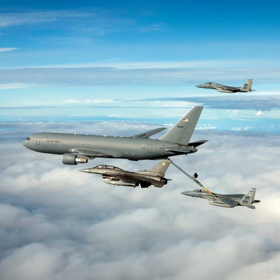 A group of jets flying in the sky above clouds.