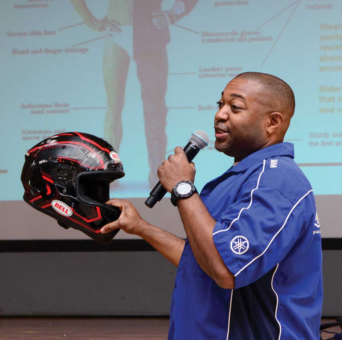 A man holding up a black and red helmet.