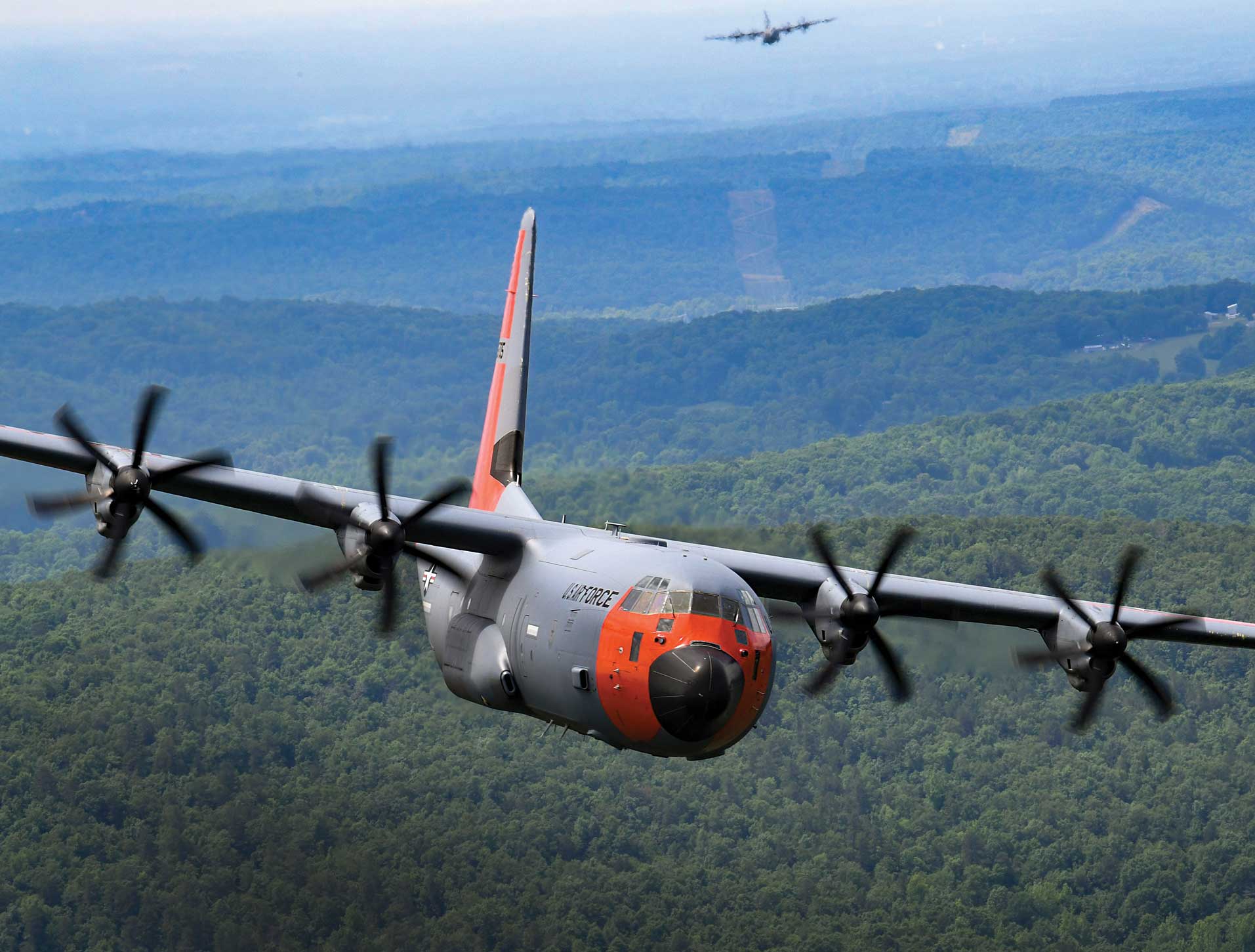 A large propeller plane flying over the top of a mountain.