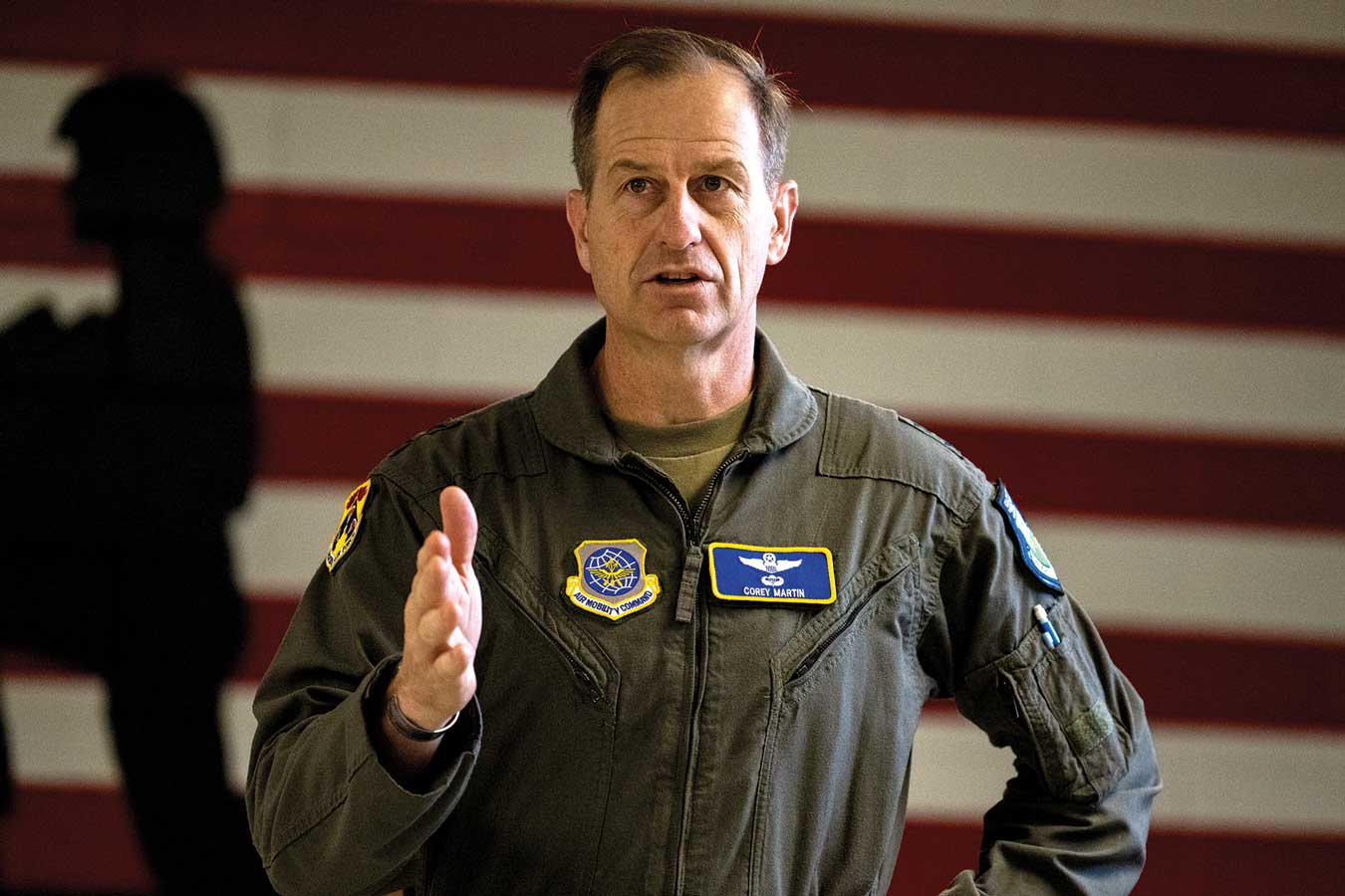 A man in an air force uniform standing next to the american flag.