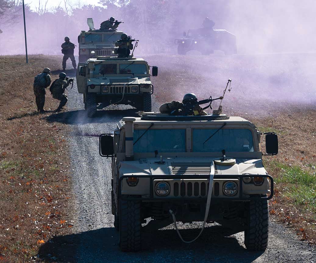 A group of military vehicles driving down the road.