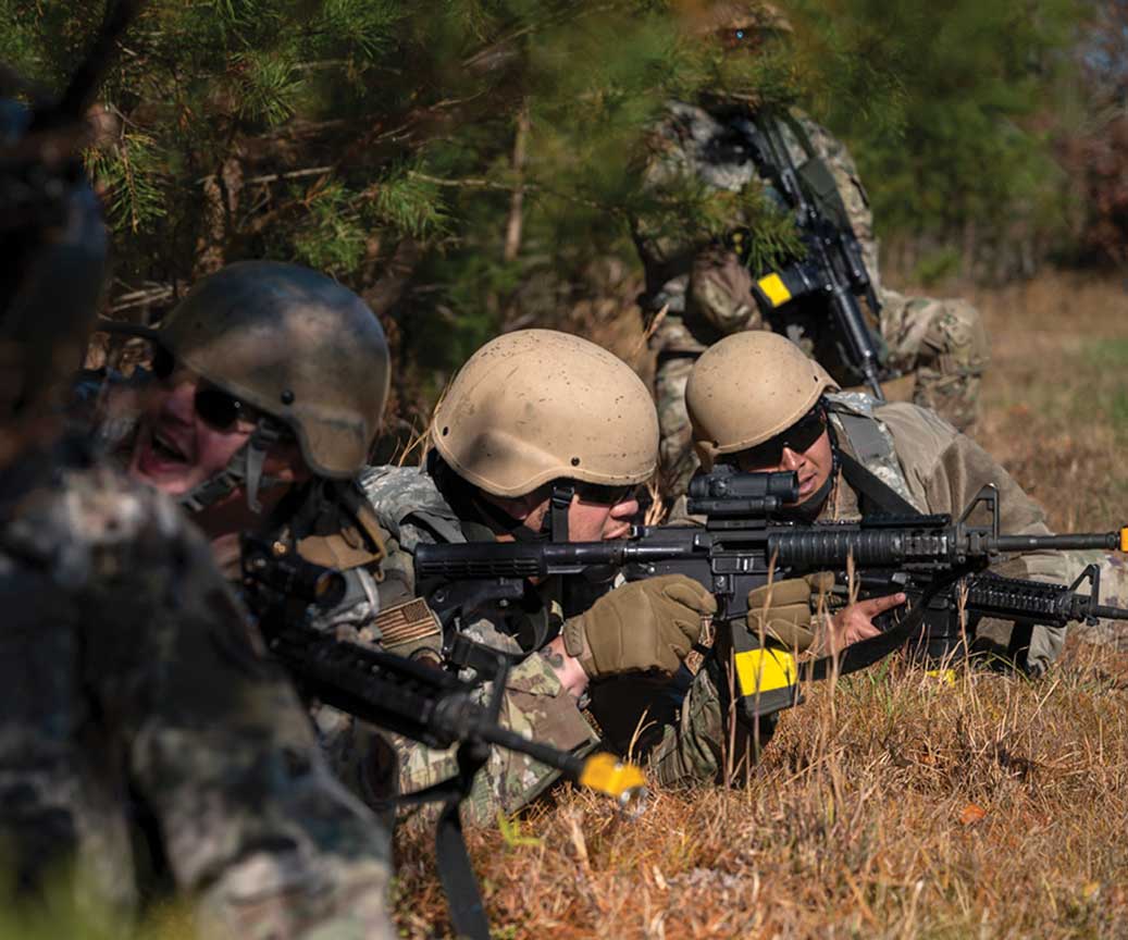 A group of soldiers are in the woods with guns.