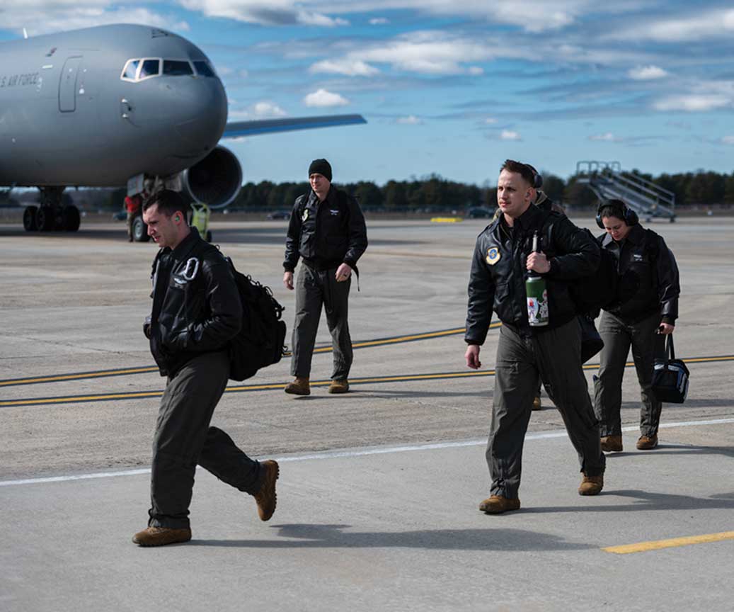 A group of men walking on the tarmac near an airplane.