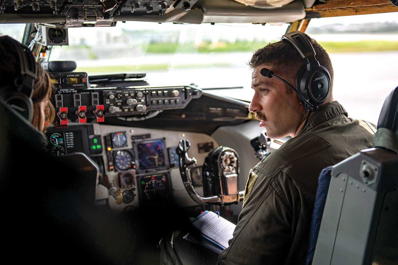 A man in headphones sitting inside of an airplane.