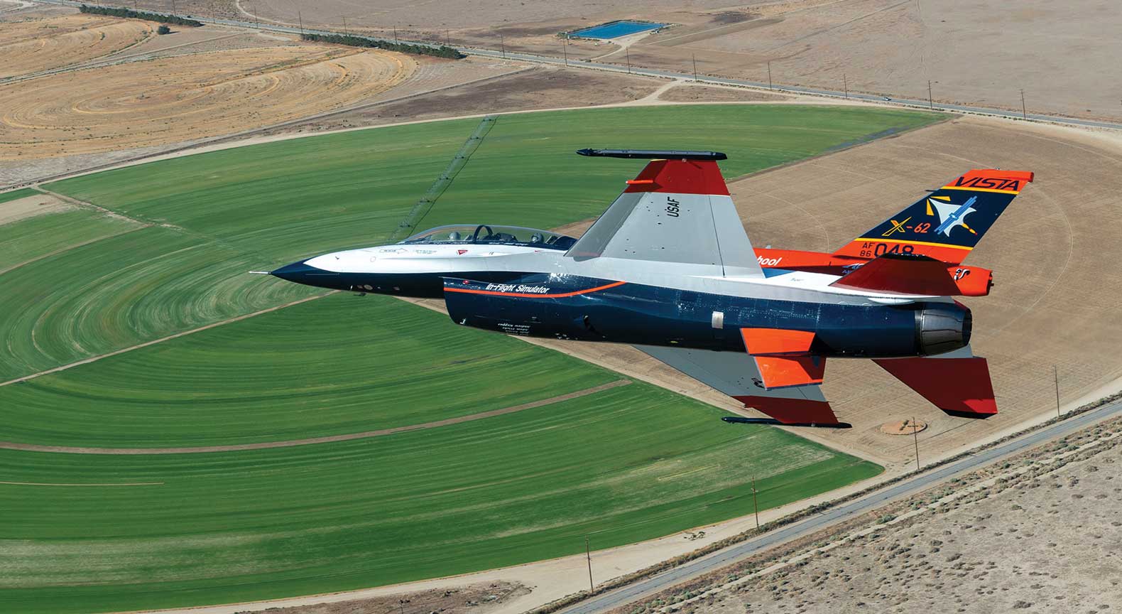 A fighter jet flying over an open field.