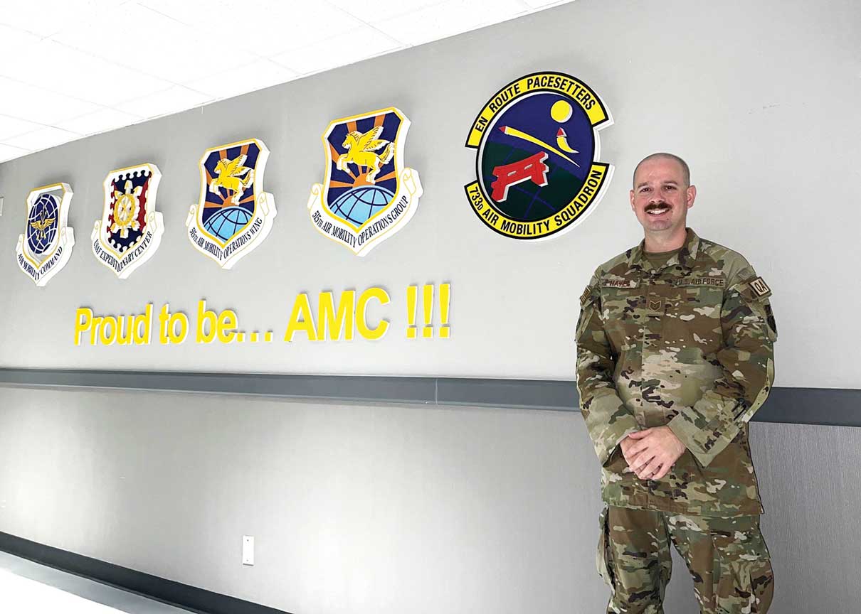 A man in military uniform standing next to four air force patches.