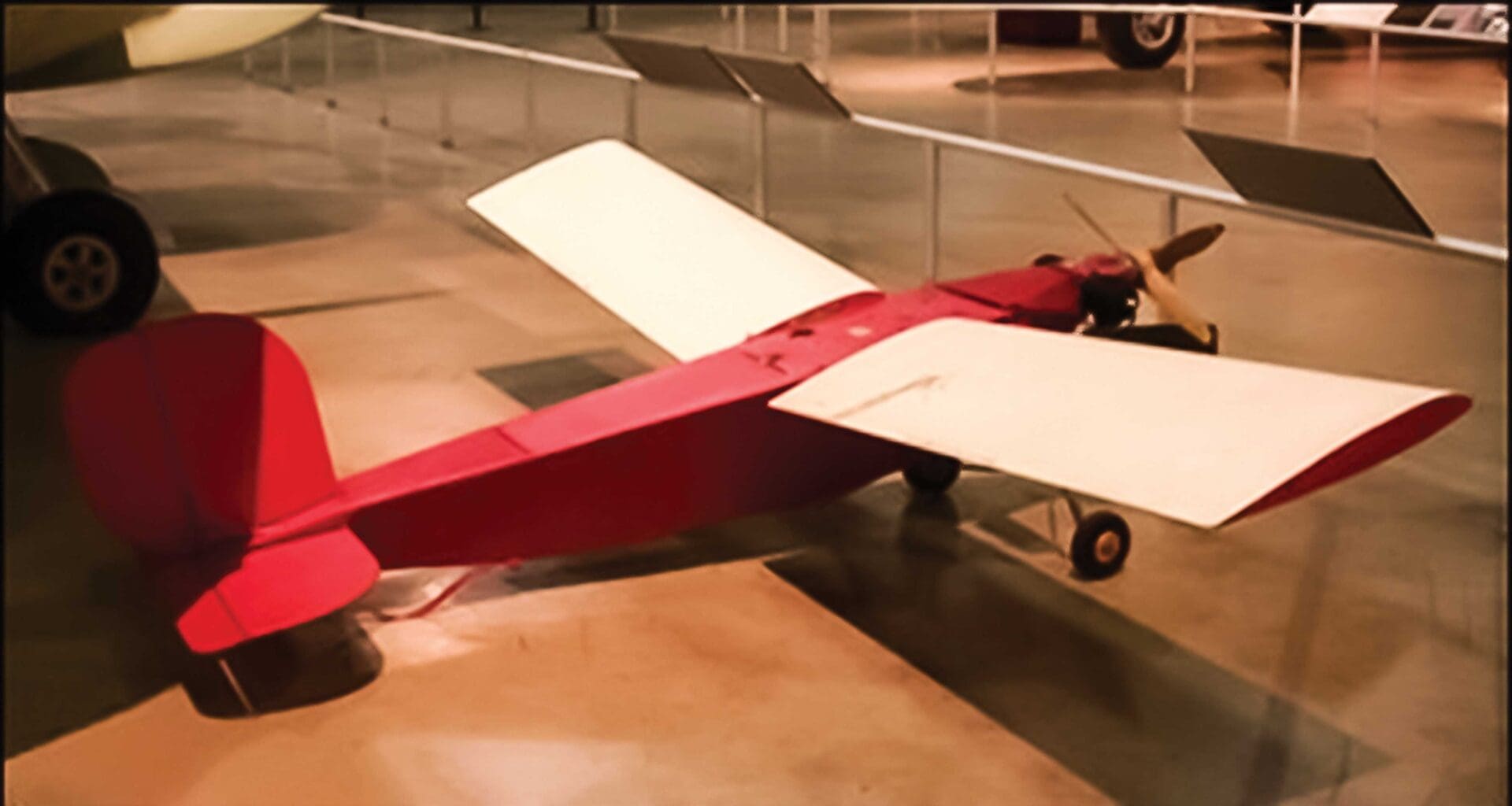 A red and white plane on display in an exhibit.