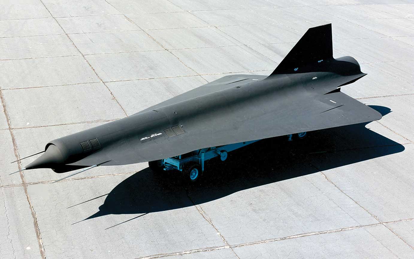 A black jet fighter sitting on top of an airport runway.