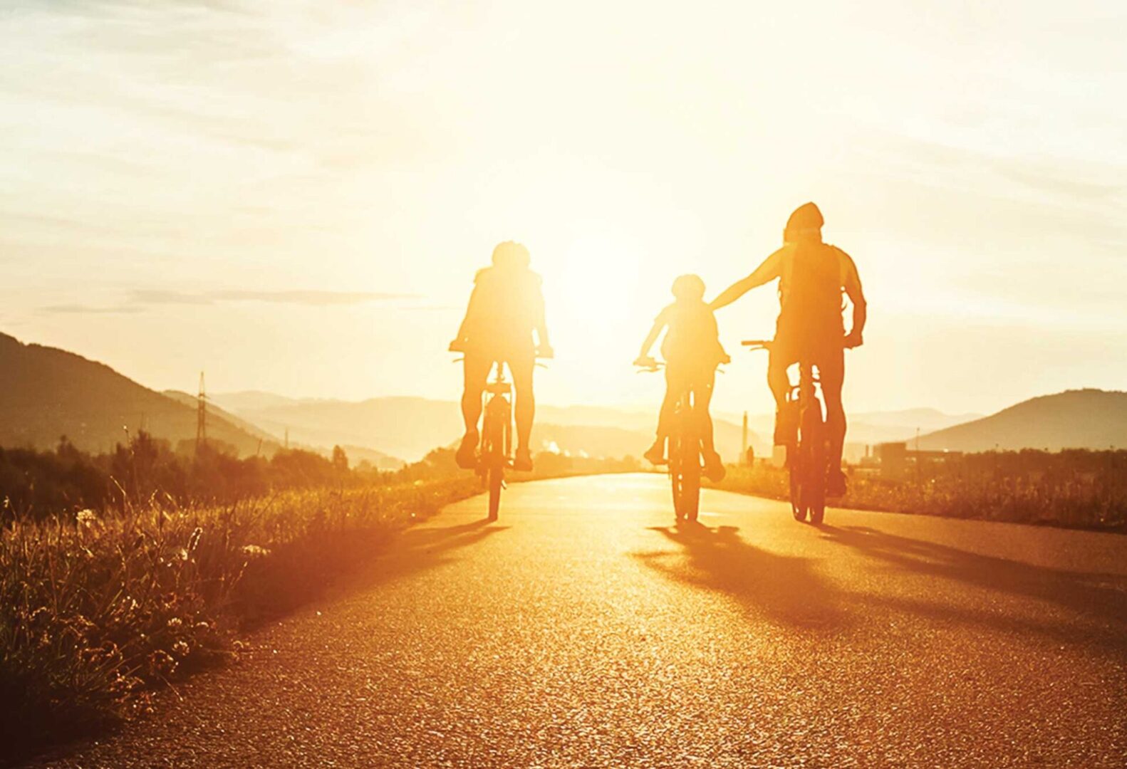 Family riding bicycles on a paved rural roadway.