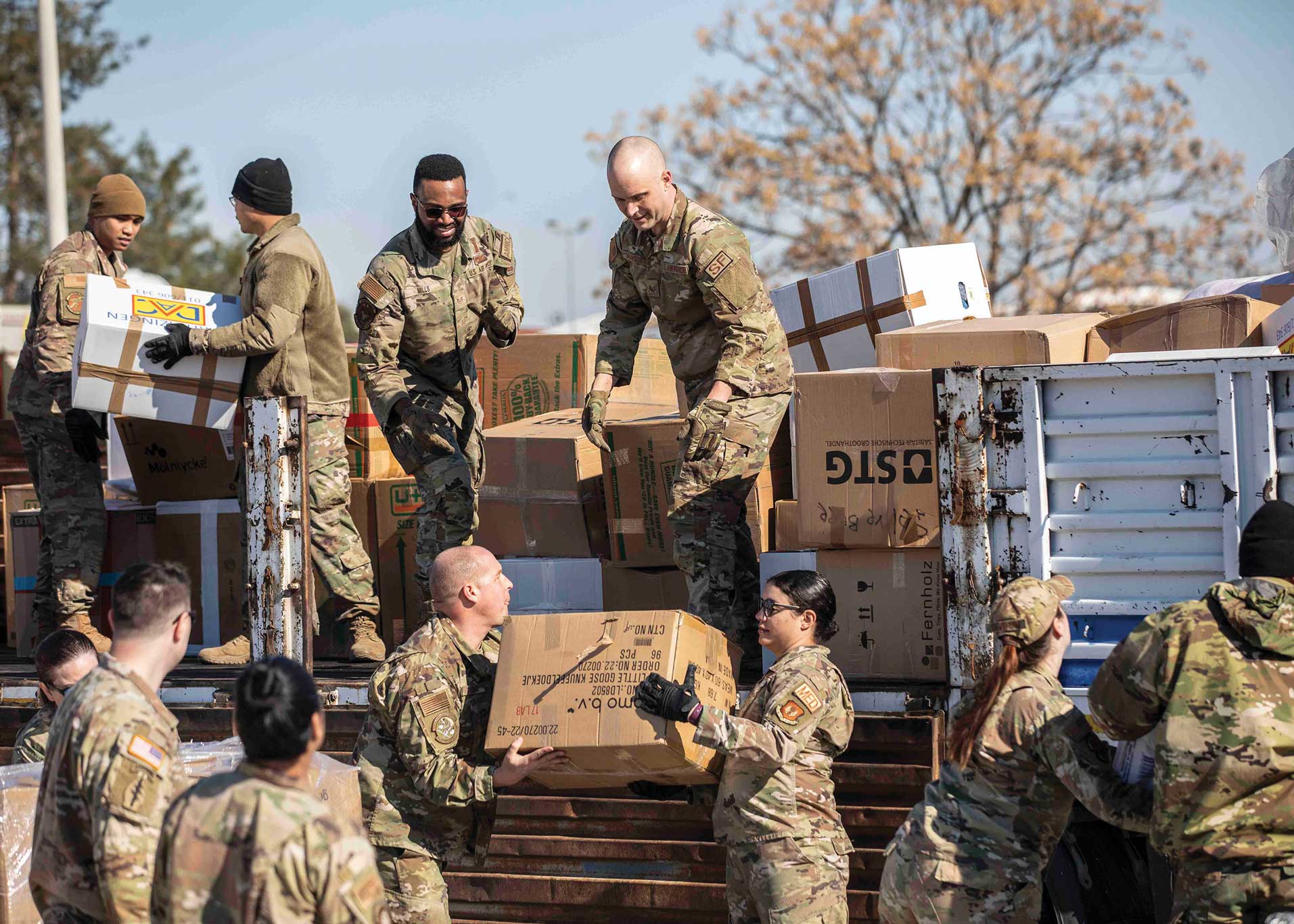 A group of soldiers loading boxes onto trucks.