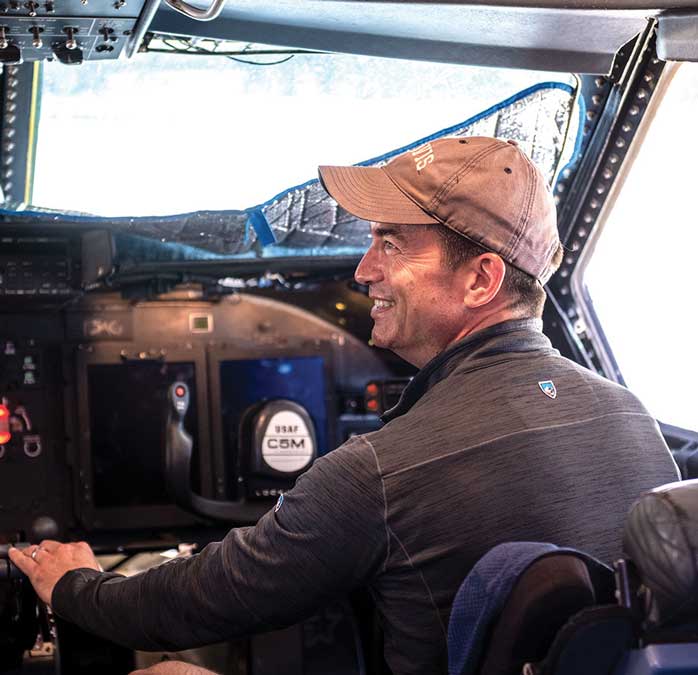 A man in glasses and hat driving an airplane.