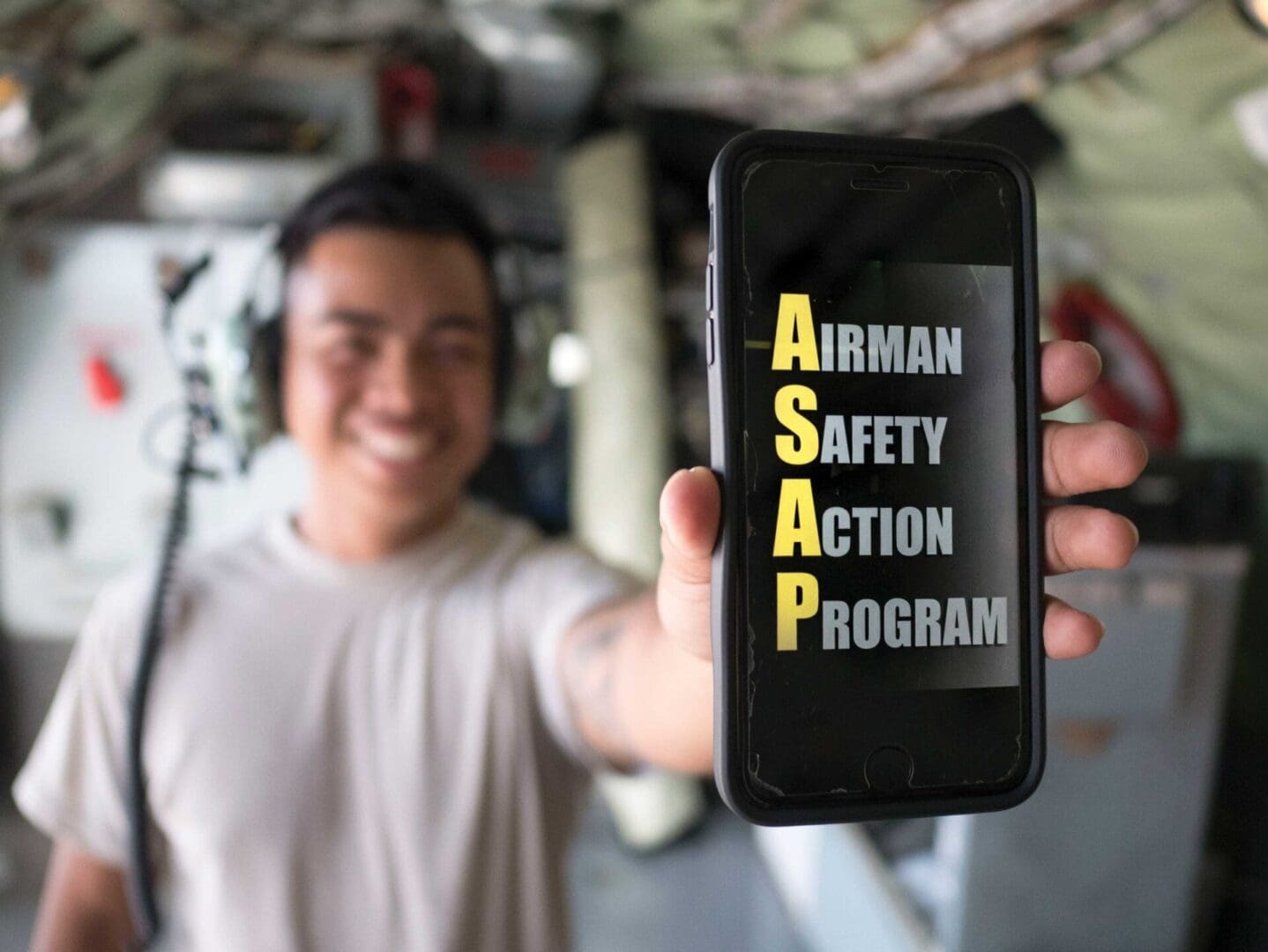 A man holding up an iphone with the airman safety action program on it.