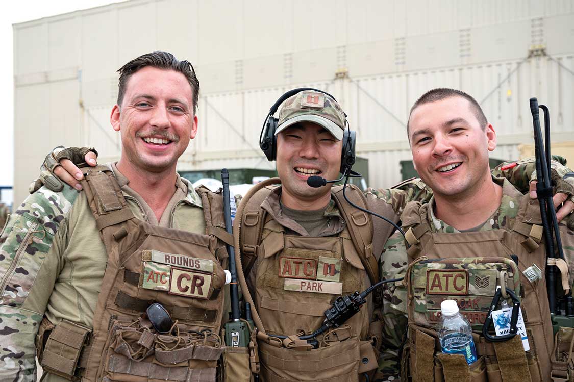 Three men in camouflage uniforms are smiling for a picture.