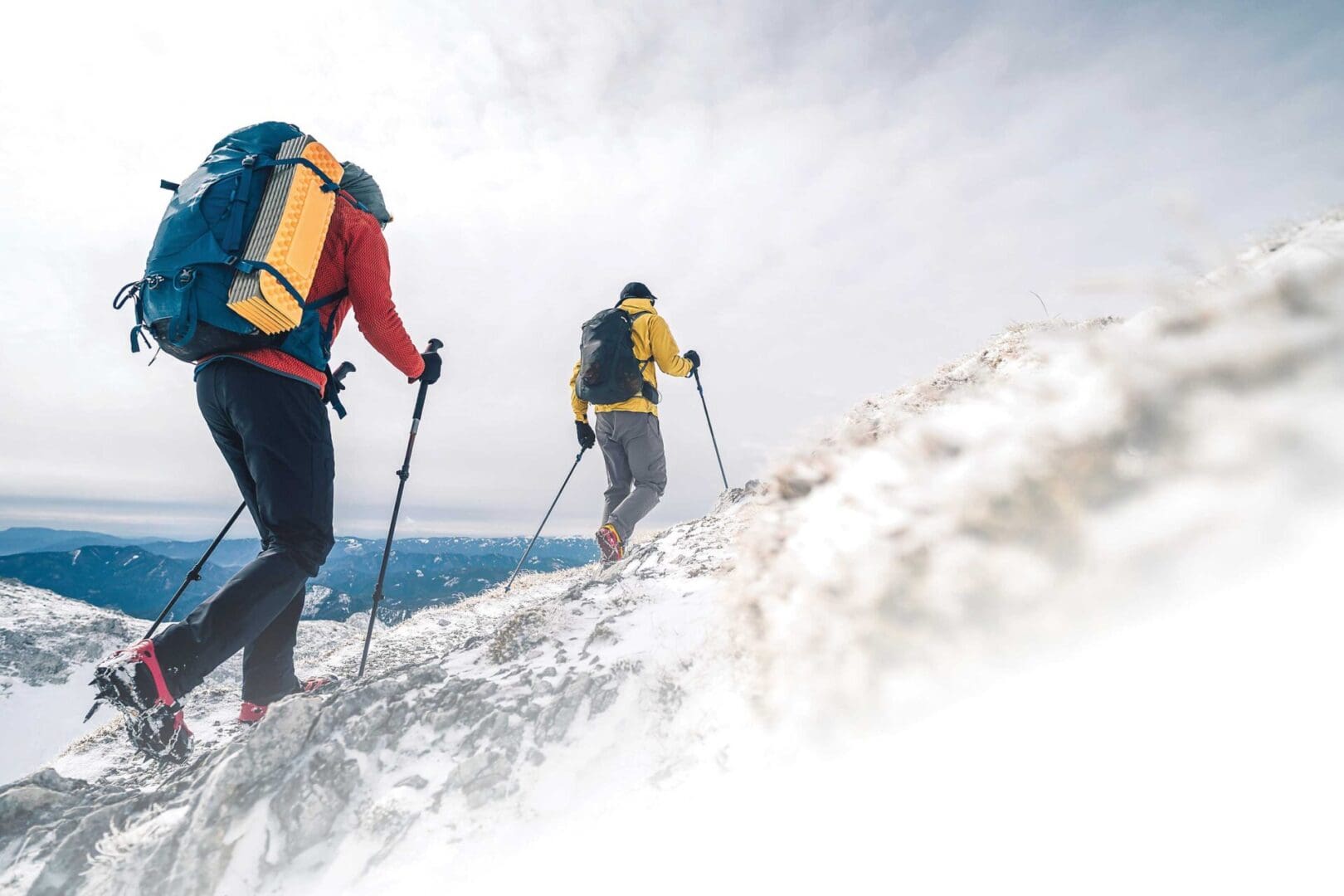 Two people are hiking up a snowy hill.