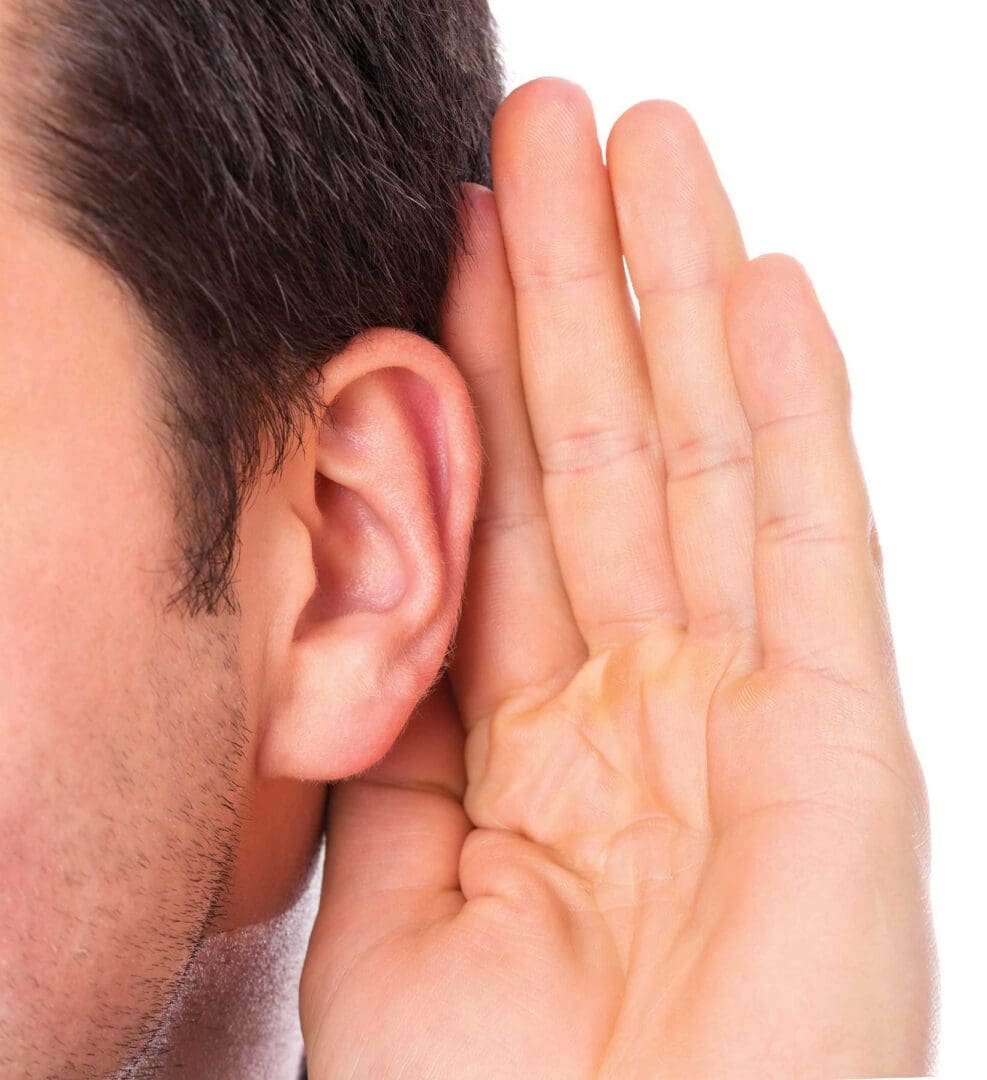 A man with his hand up to the side of his ear.