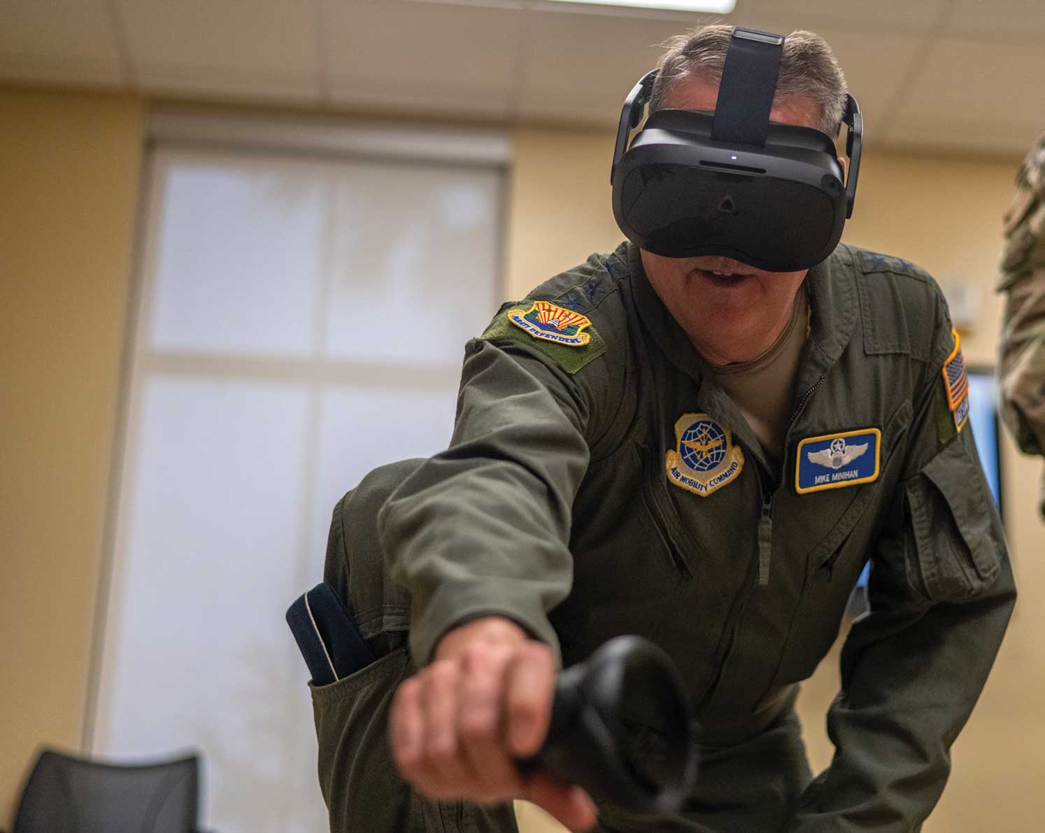 A man in an air force uniform wearing goggles and holding a controller.