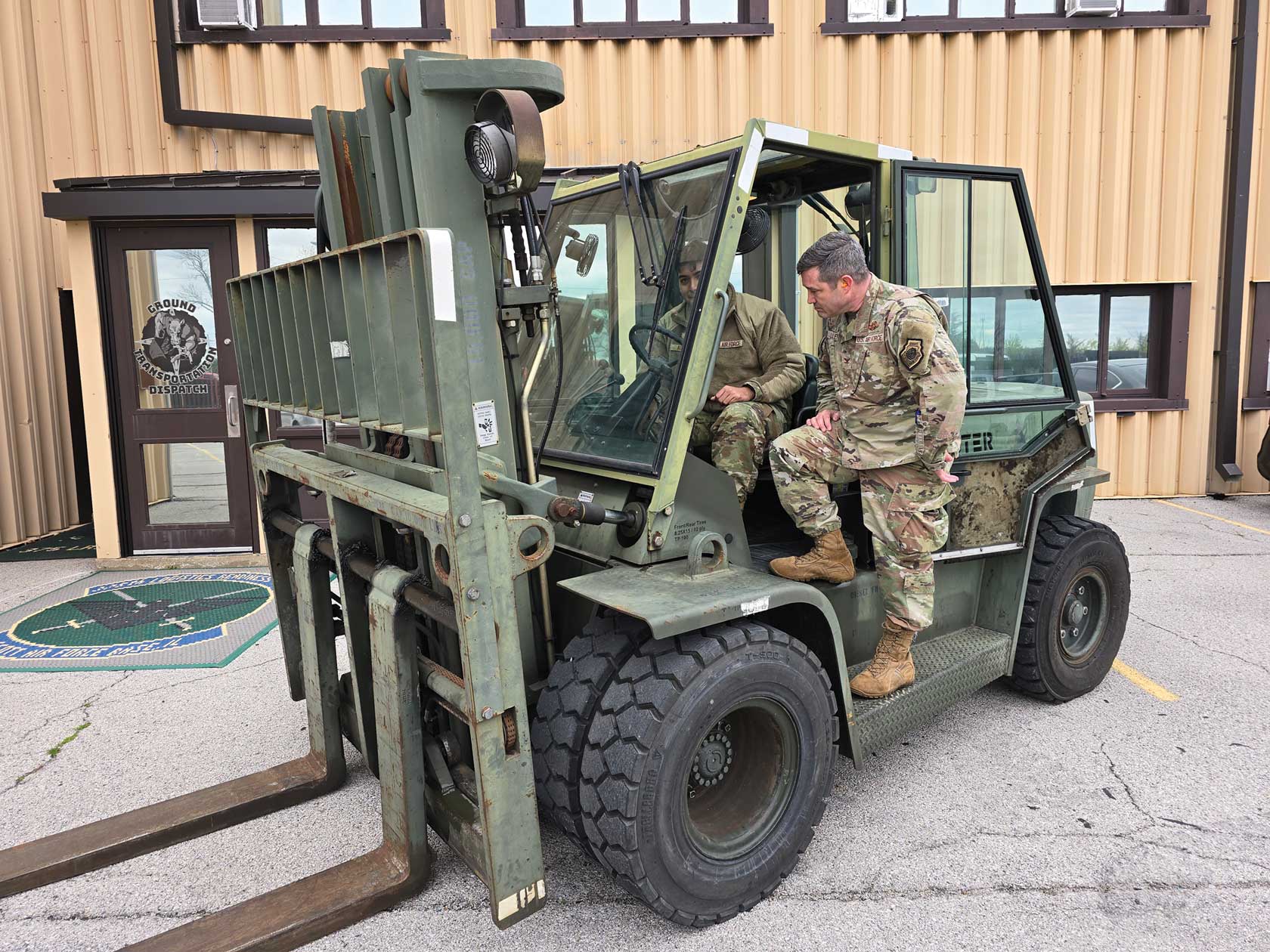 A man in uniform sitting on the back of a forklift.