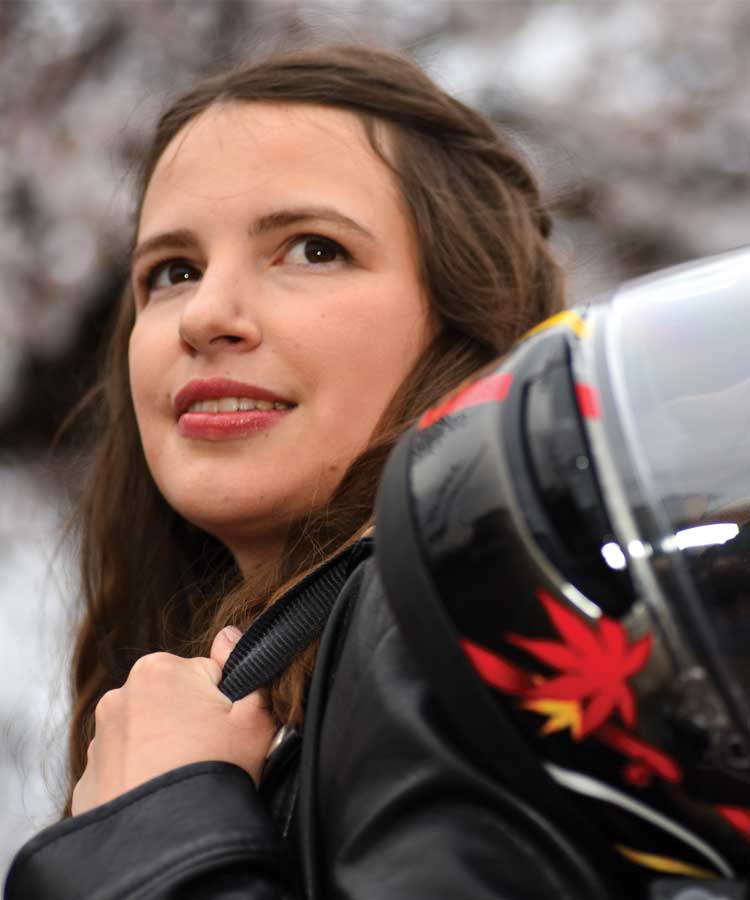 A woman in black jacket holding motorcycle helmet.