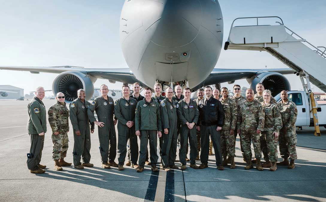 Lt Gen John Healy poses with members of the 349th Air Mobility Wing on the flightline at Travis Air Force Base, CA, in front of a KC-46A Pegasus aircraft.