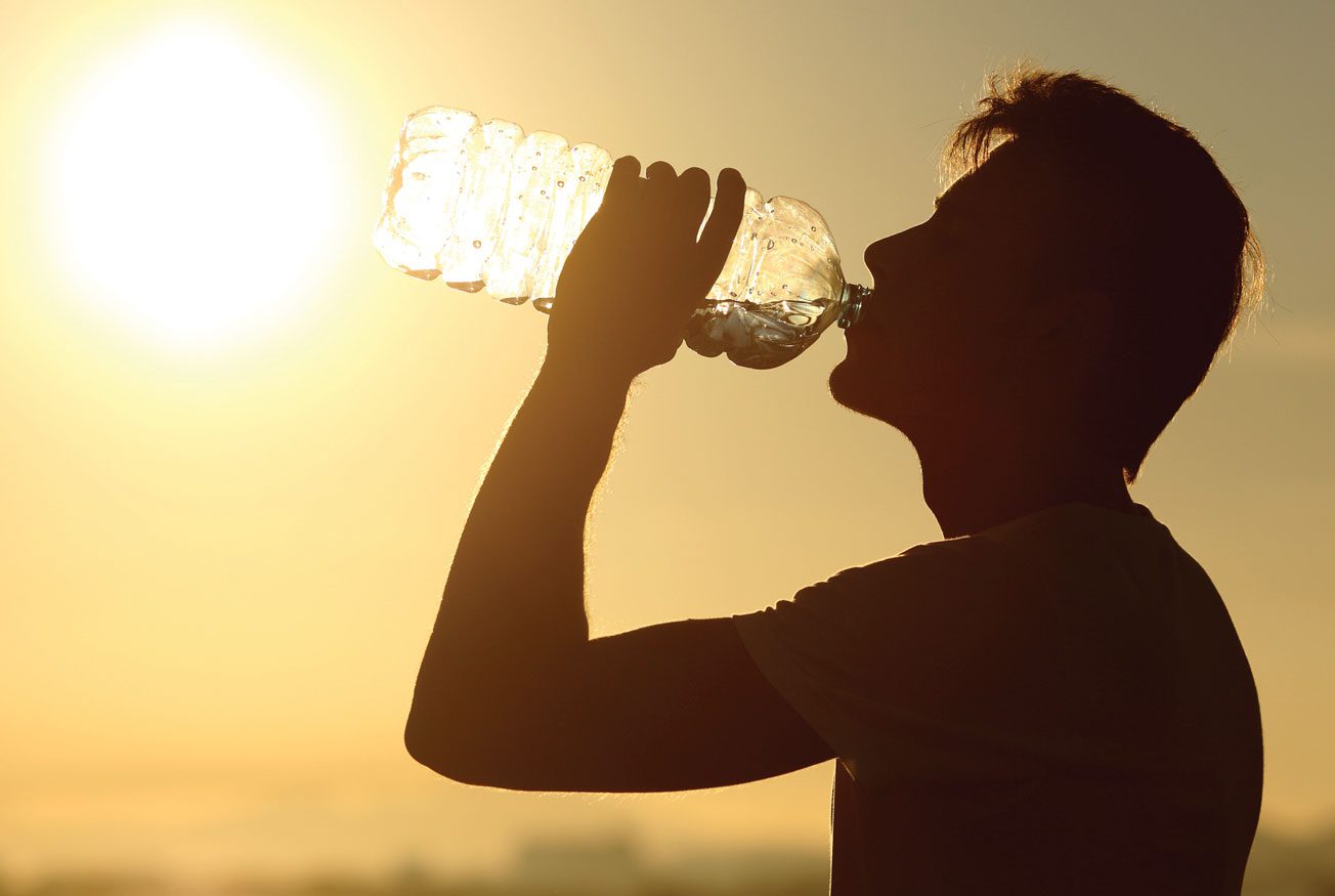A silhouette of a man drinking water from a bottle. Description generated by AI